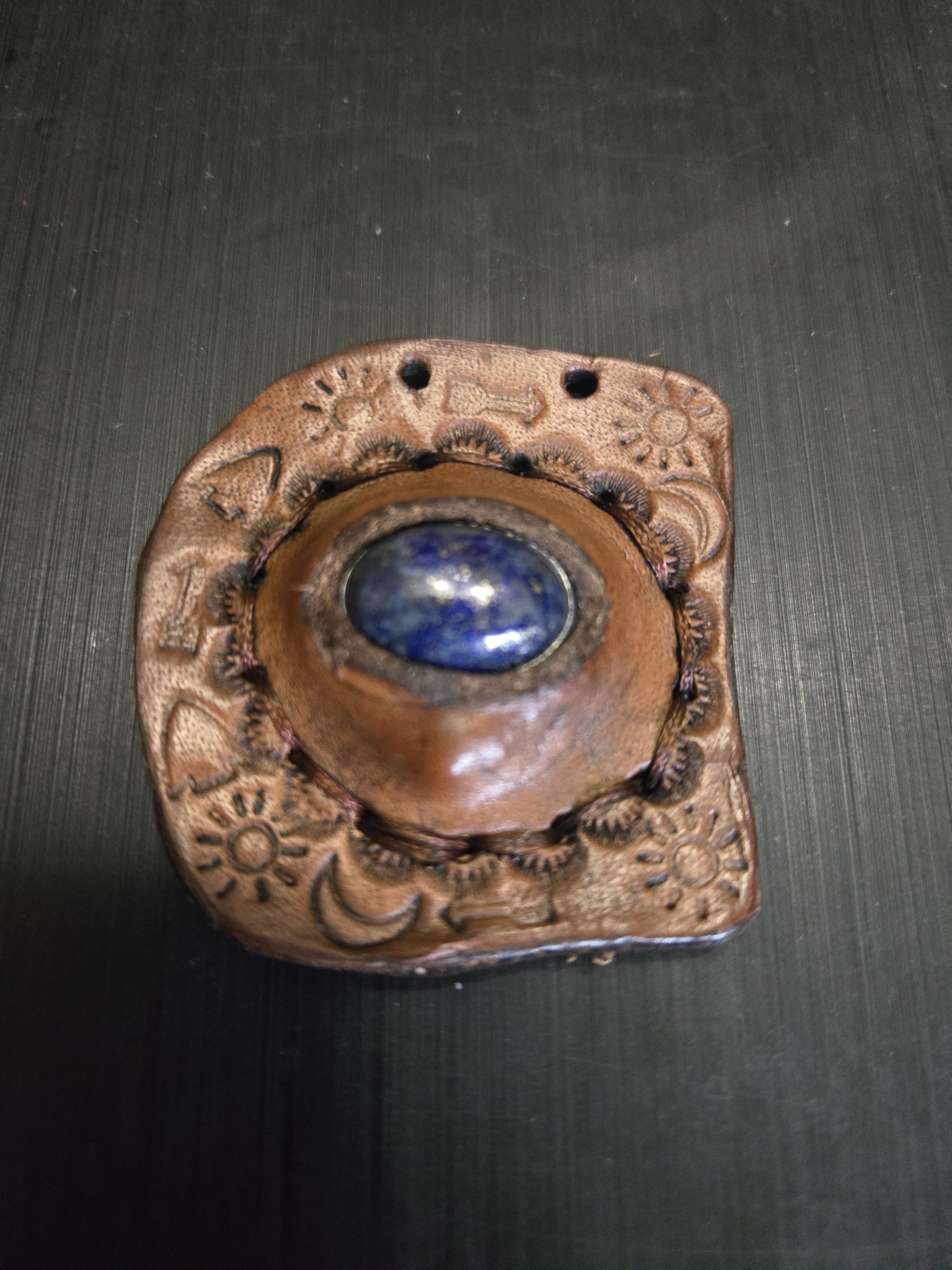 Stock 148 hand-tooled leather pendant with a lapis lazuli center stone and sun, moon, and arrow stamping