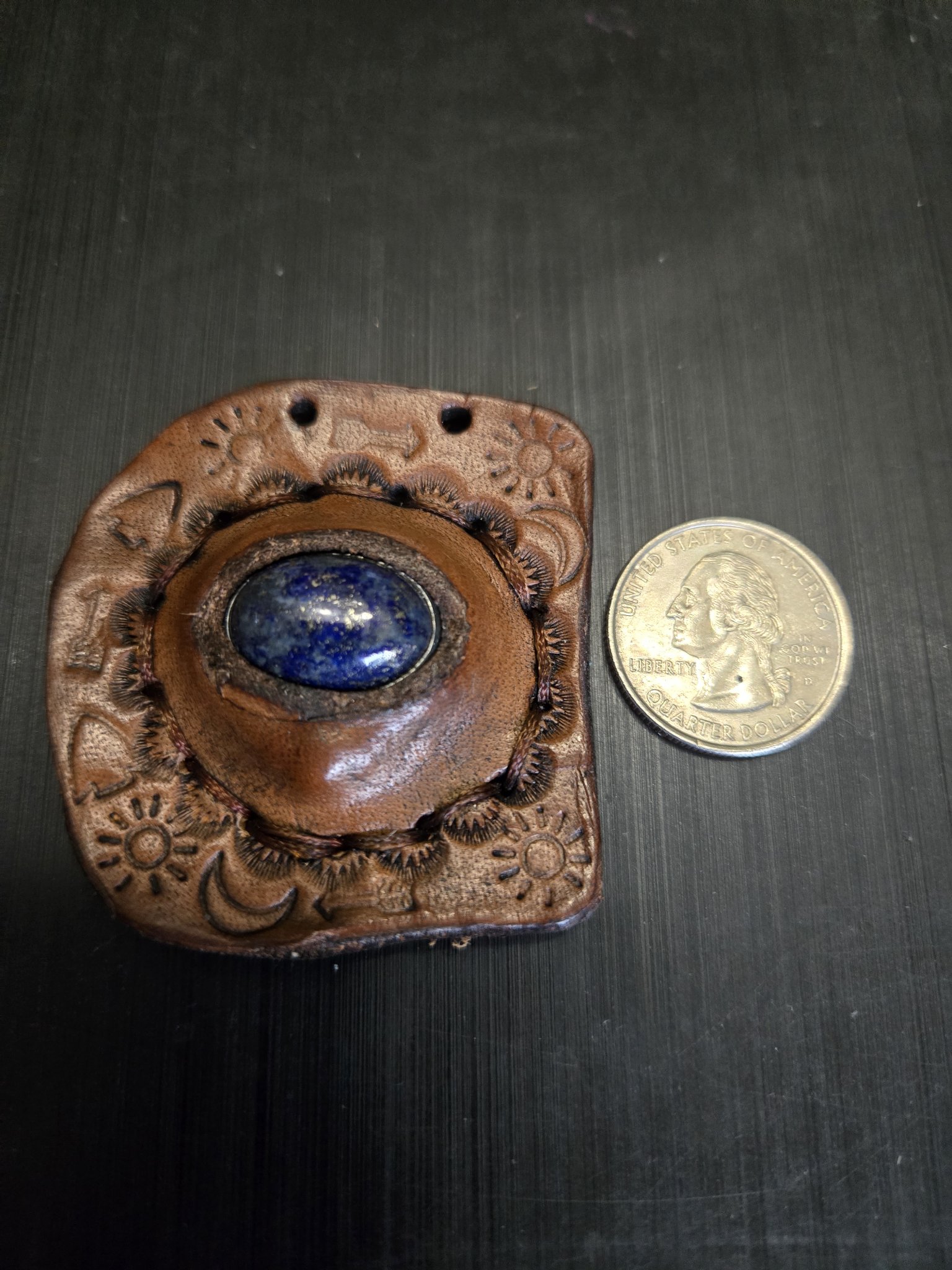 Stock 148 leather lapis pendant beside a quarter showing it is approximately two and a half inches across