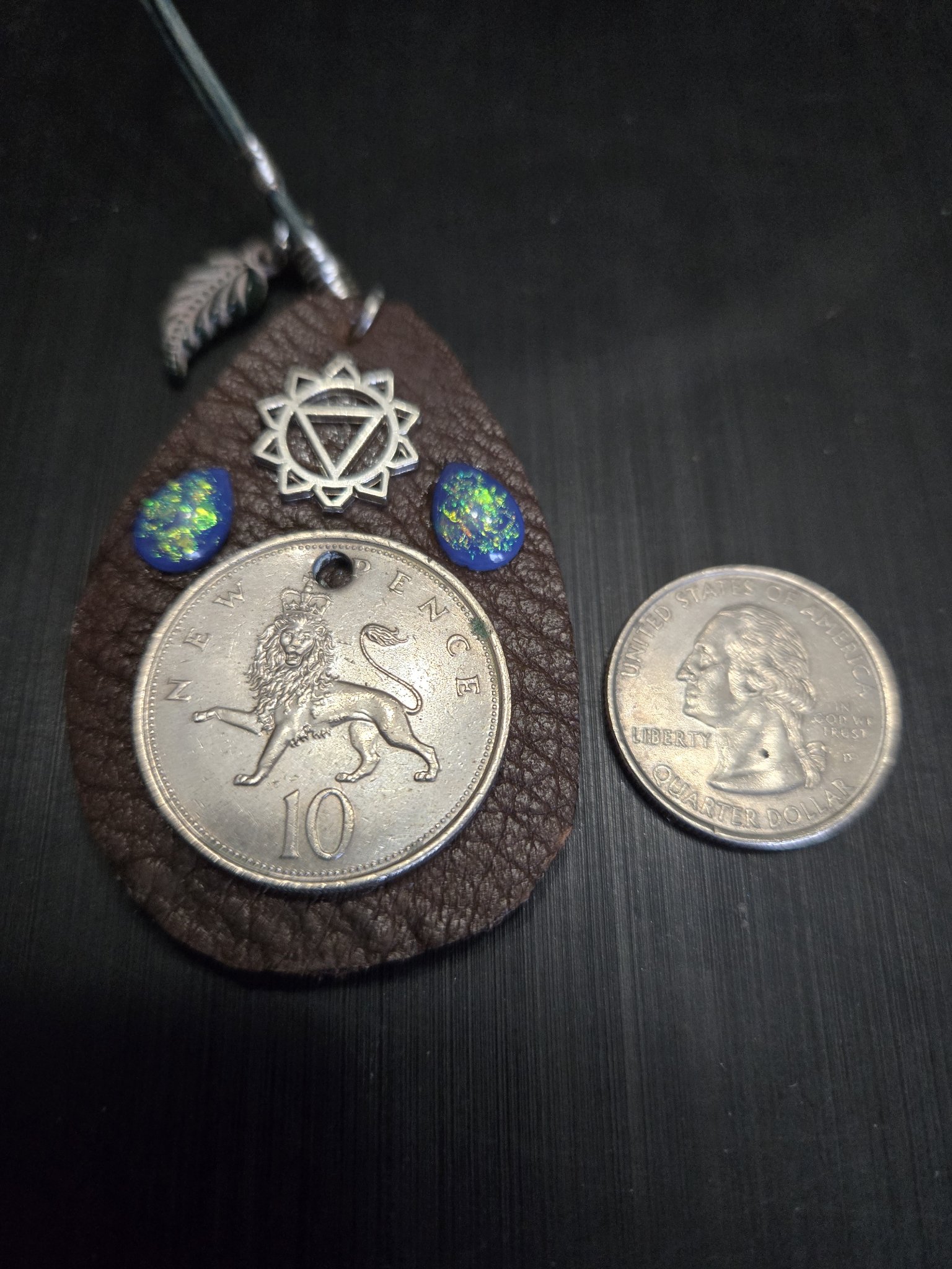 Close-up of stock 150 showing the lion coin, chakra charm, blue fire opal teardrops, and a quarter for scale
