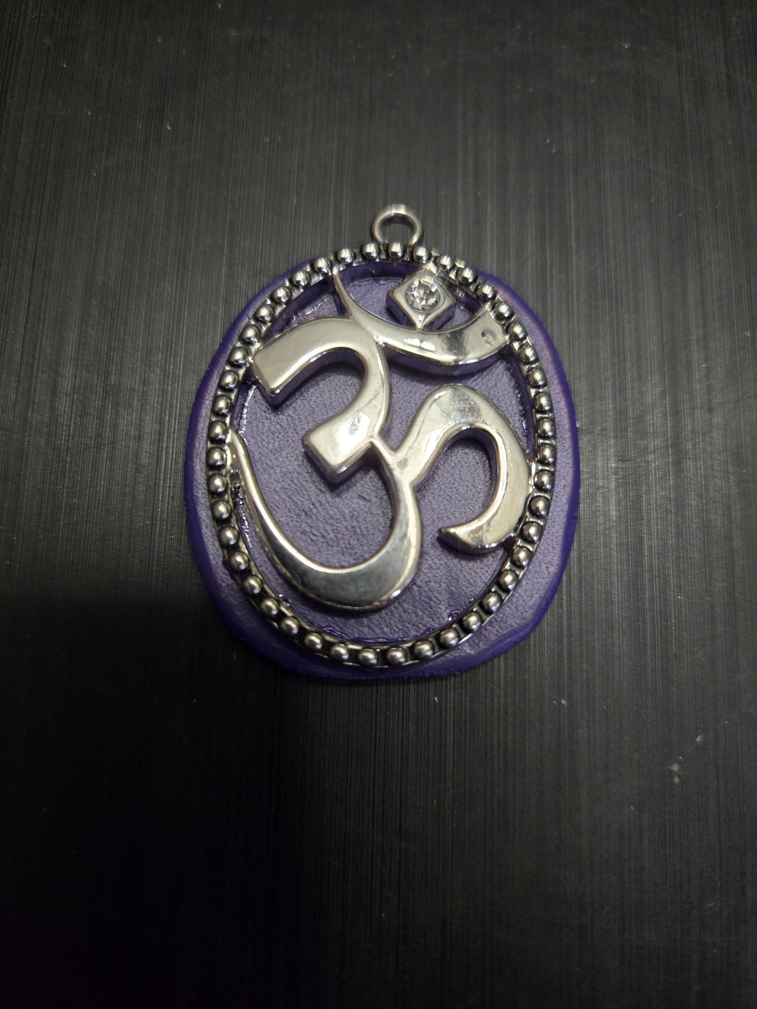 Stock 151 purple leather pendant with a silver-tone Om symbol, crystal accent, and beaded oval frame