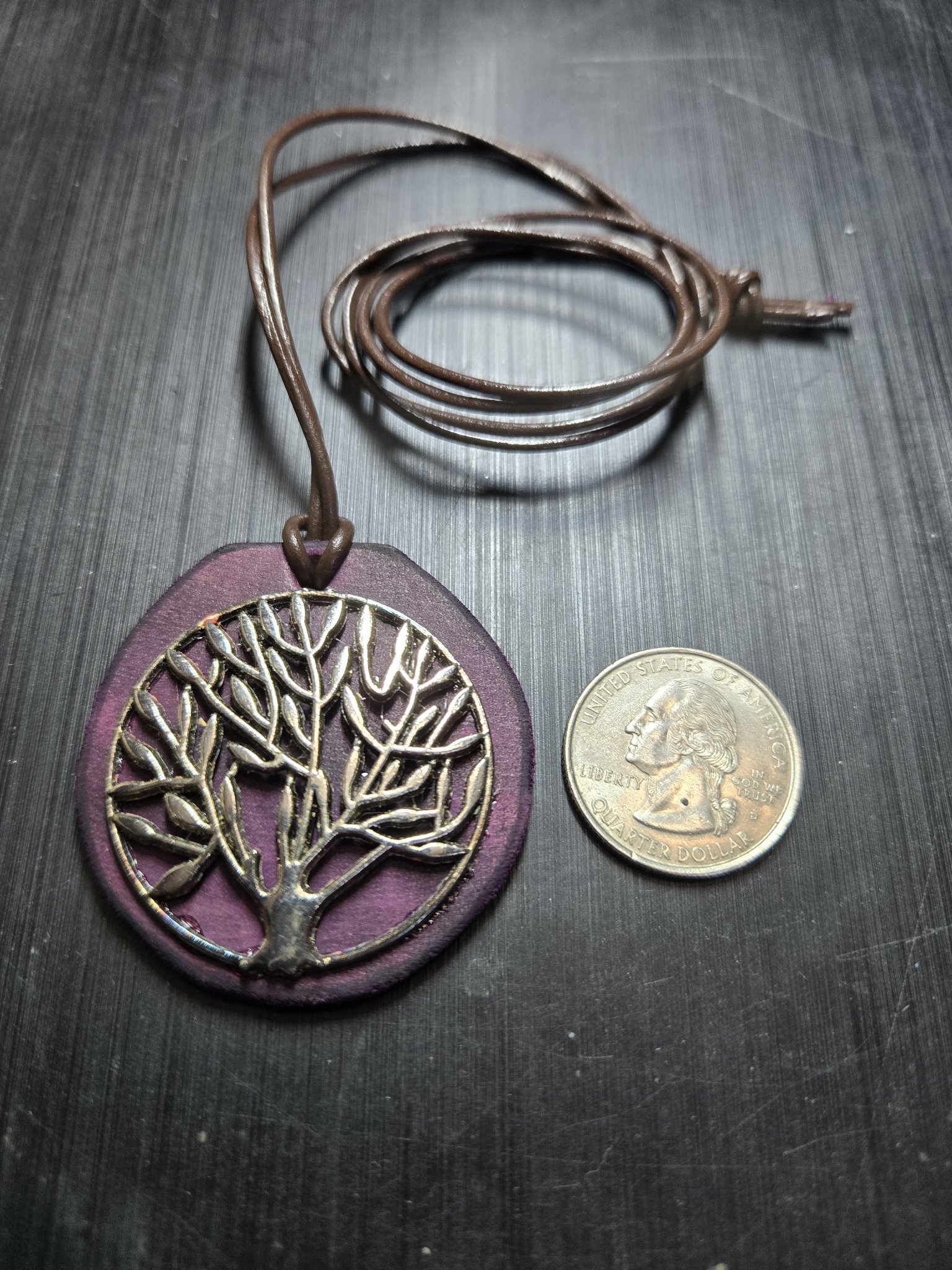 Stock 154 dark purple leather Tree of Life pendant beside a quarter showing it is approximately two inches across