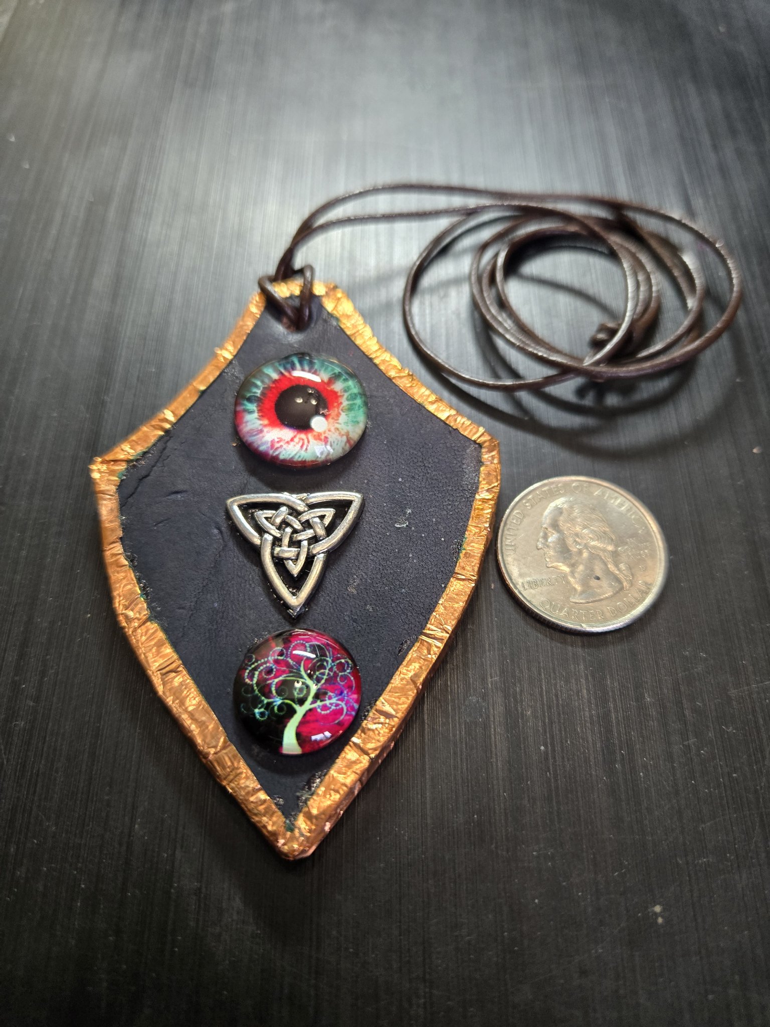 Stock 161 copper-framed black leather pendant beside a quarter for scale