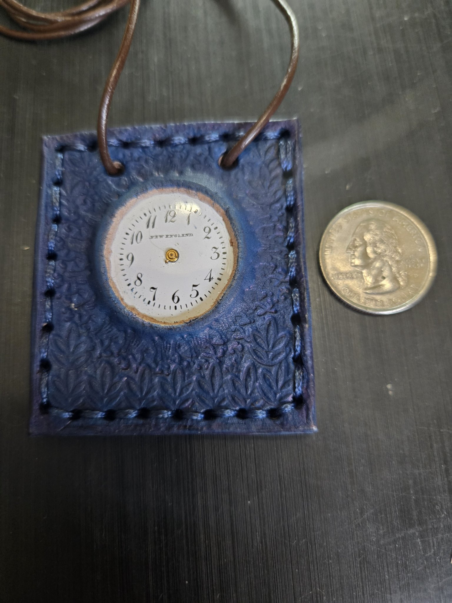 Stock 163 blue leather clock face pendant beside a quarter for scale