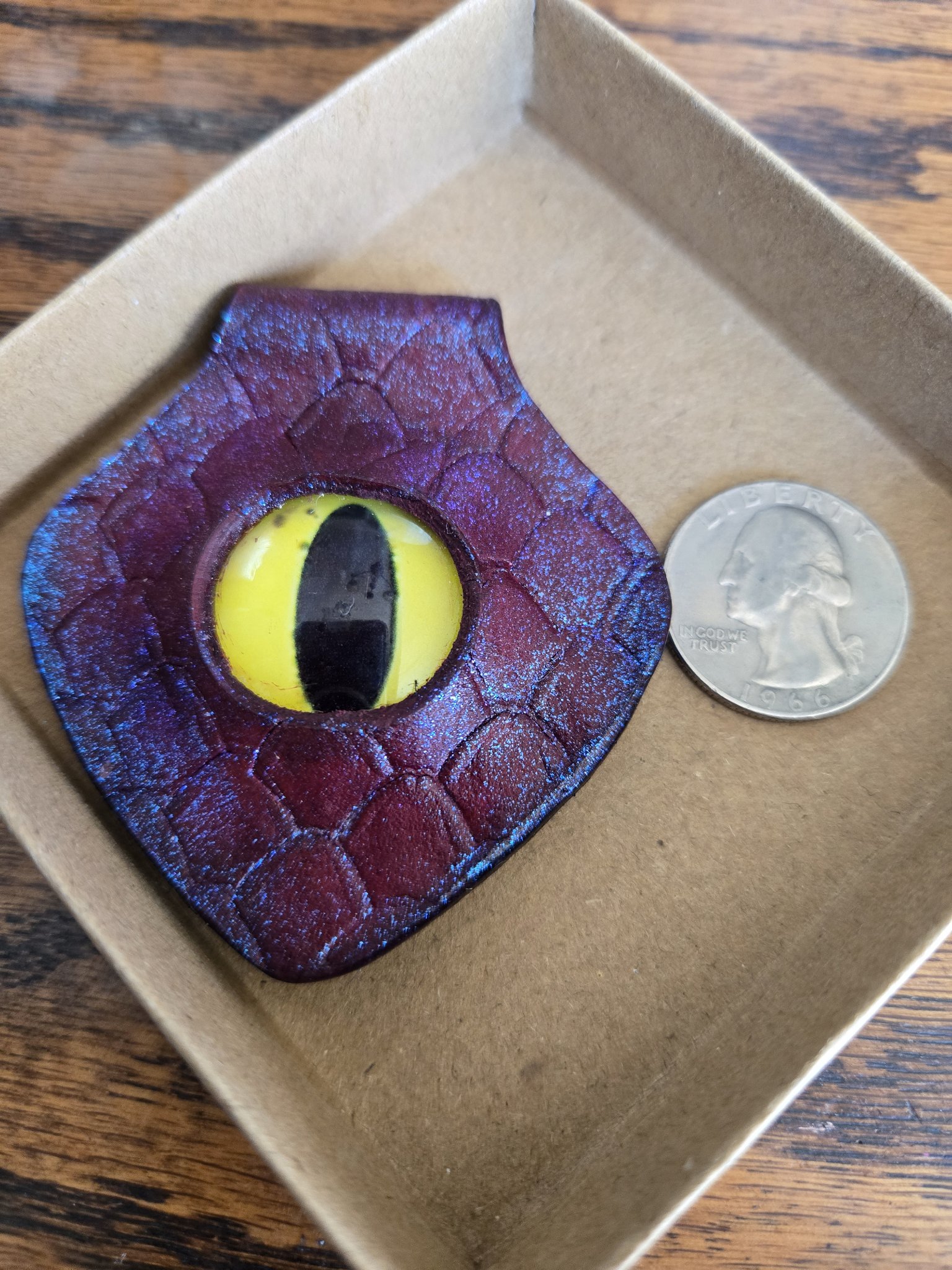 Stock 172 red leather dragon eye pendant beside a quarter for scale