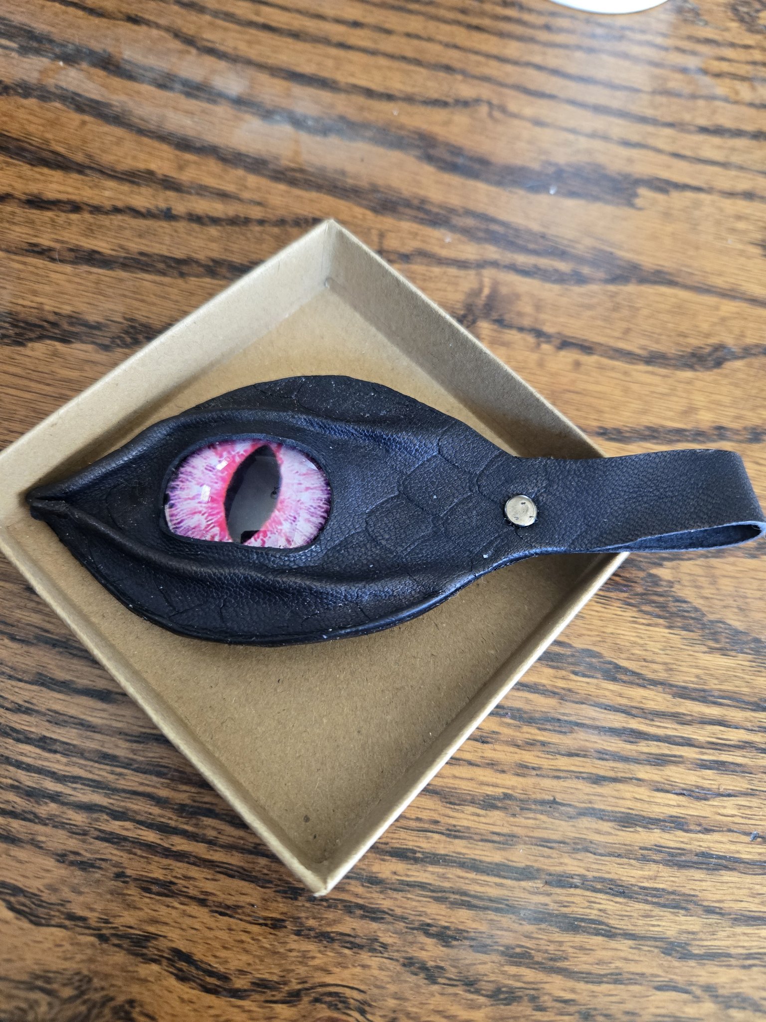 Stock 173 black leather keychain with dragon scale stamping, a red dragon eye cabochon, and a snap-closure loop, shown in a front close-up