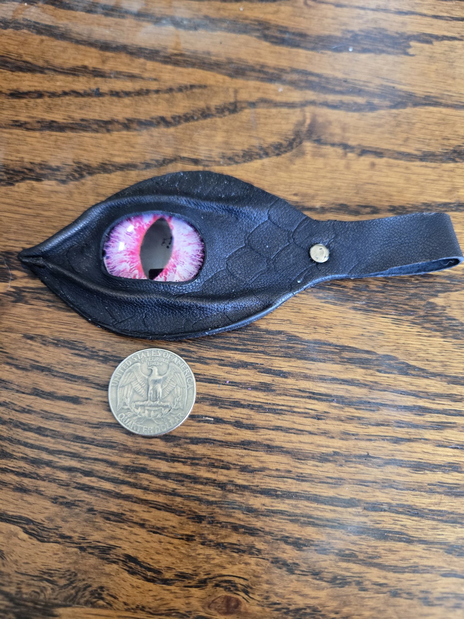 Stock 173 black leather dragon eye keychain beside a quarter for scale