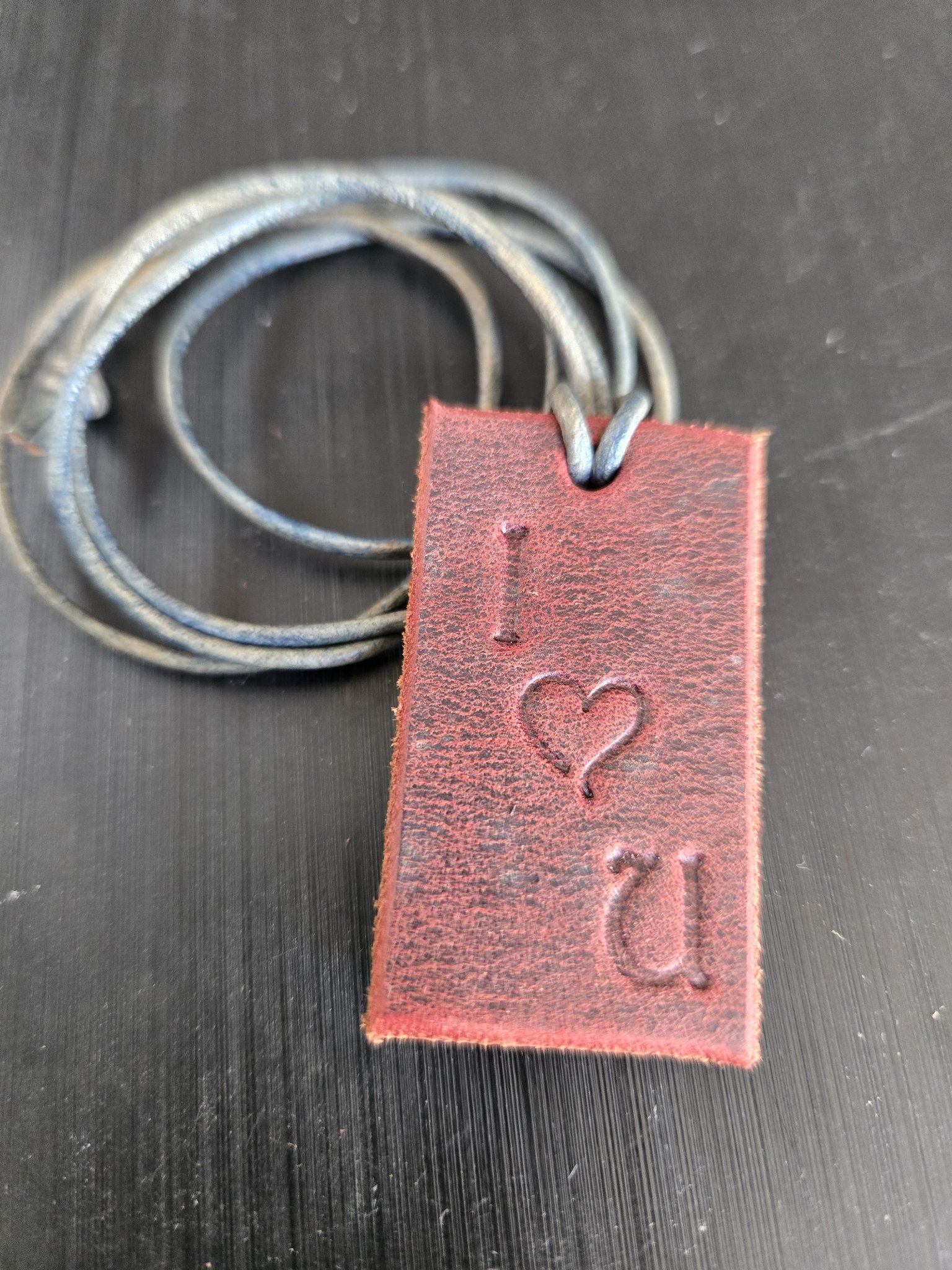 Stock 177 brown saddle leather rectangular pendant hand-stamped I love you, shown in a front close-up