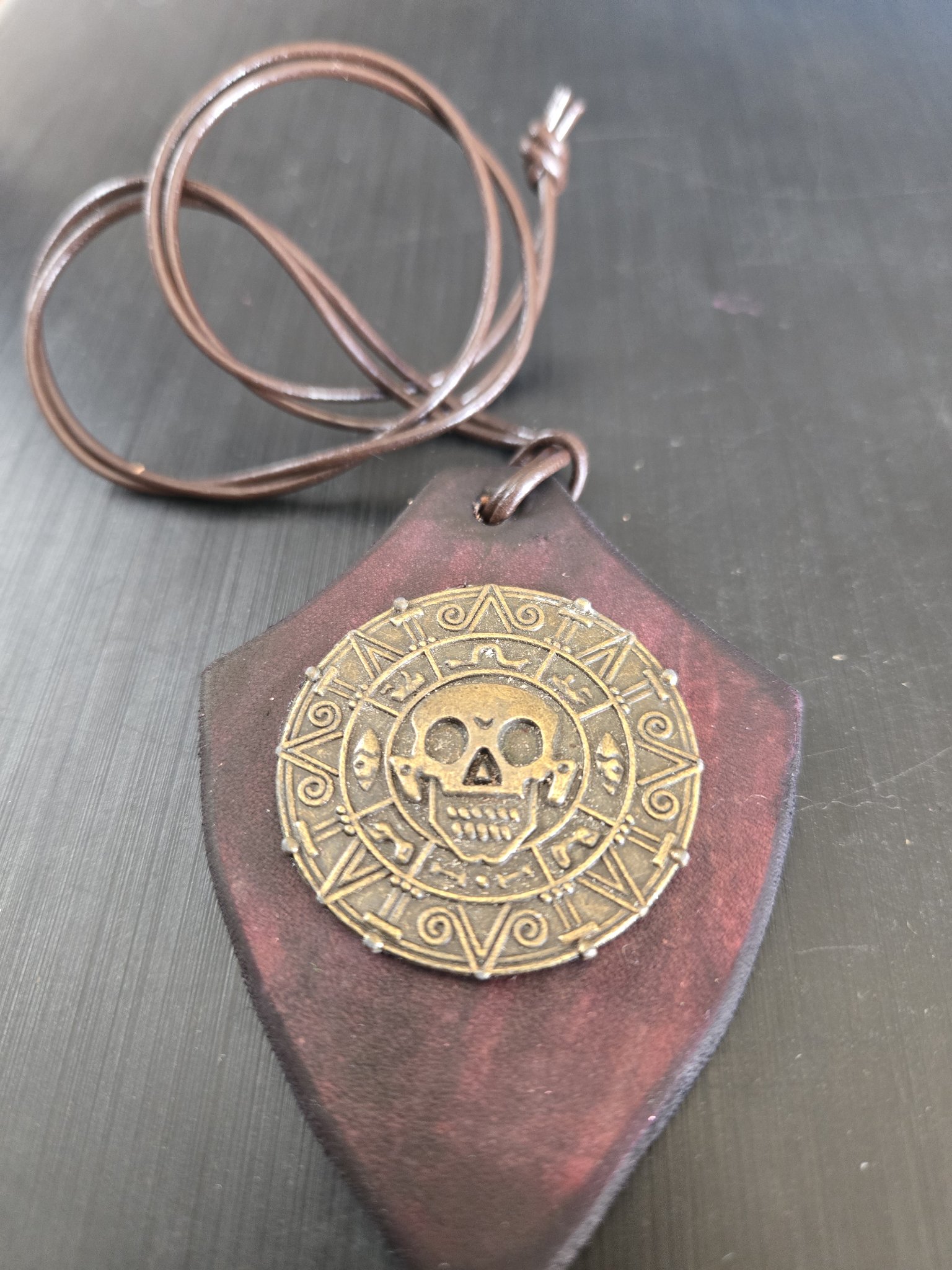 Alternate angle of stock 179 showing its dark maroon leather shield and brass-tone Aztec-style skull coin medallion