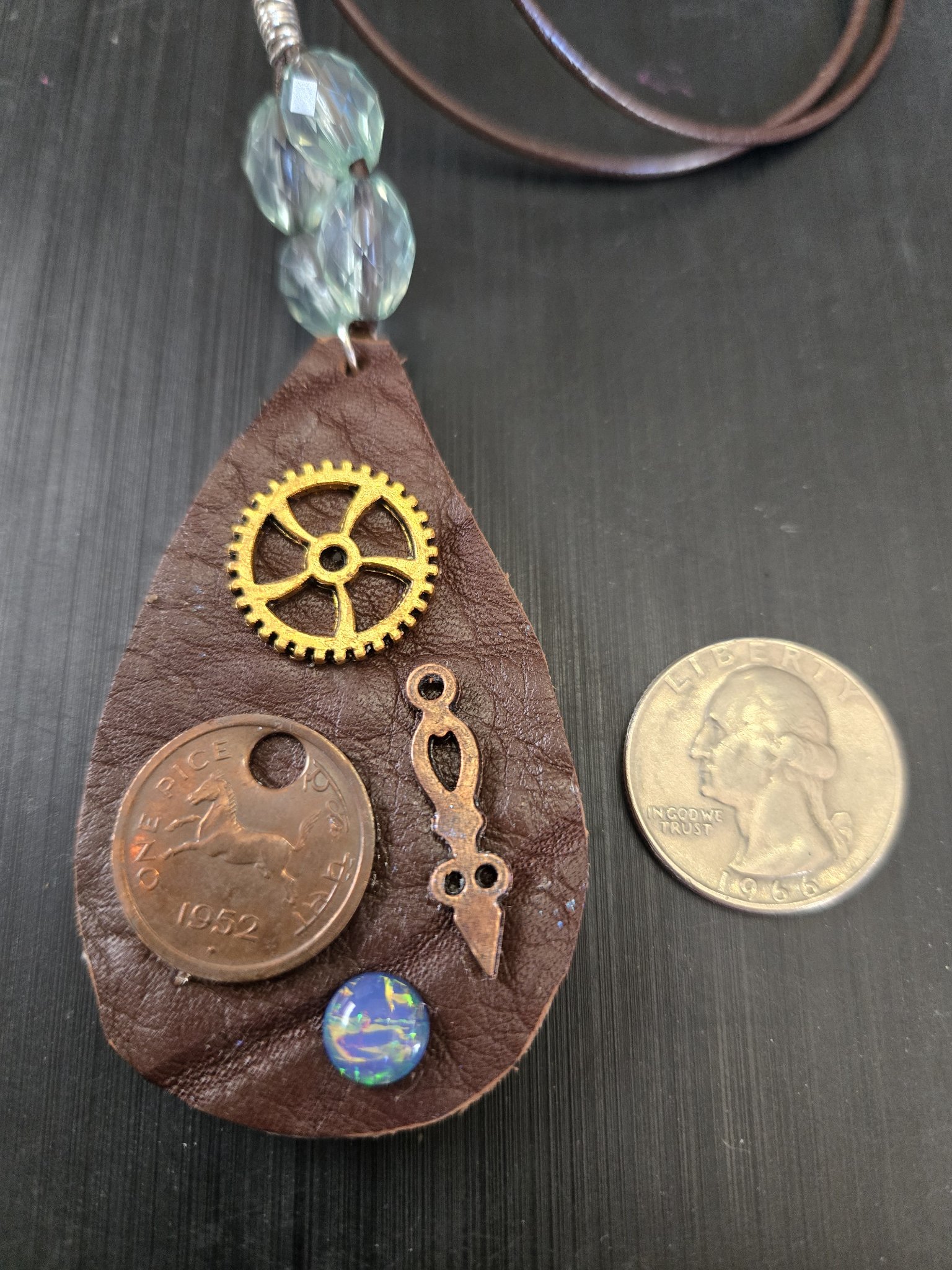 Front of stock 180 steampunk buffalo leather pendant beside a quarter for scale