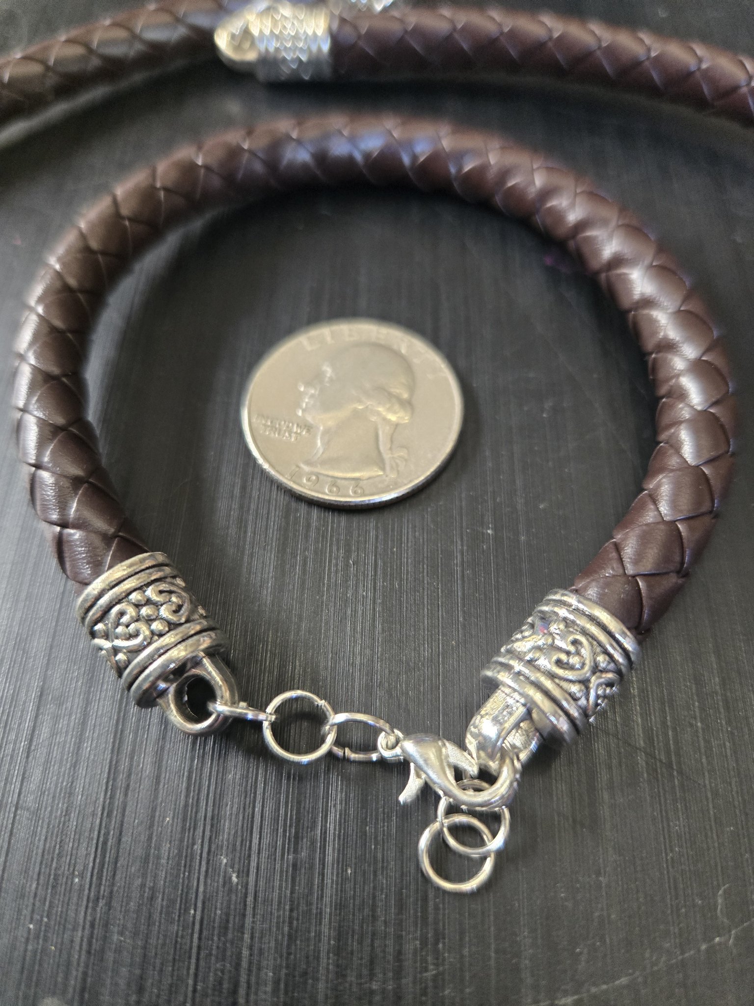 Bracelet from stock 194 braided brown leather set shown close up beside a quarter for scale
