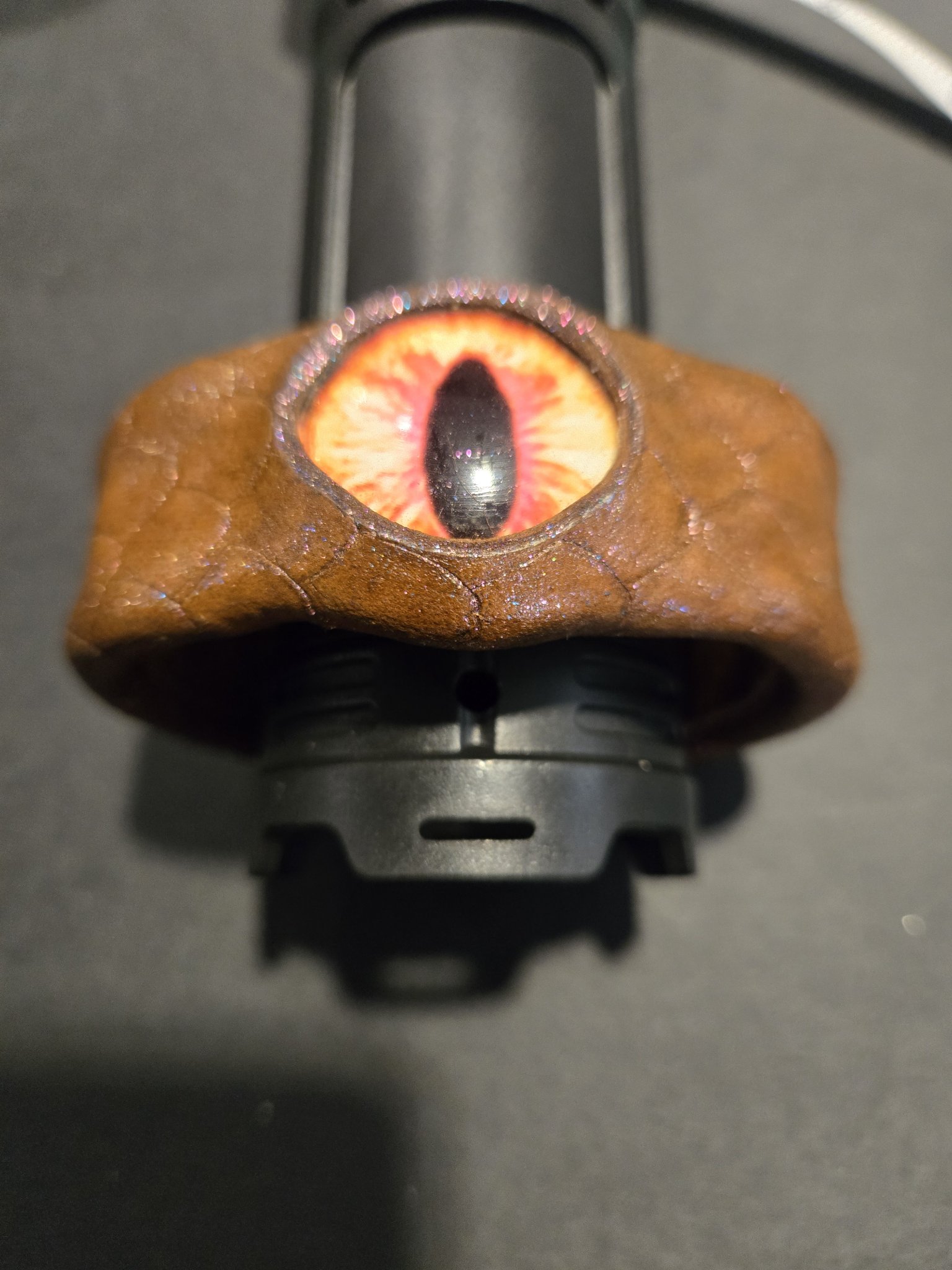 Stock 218 dragon scale leather cuff with a striking red and cream dragon eye and pinkish sheen, shown from above
