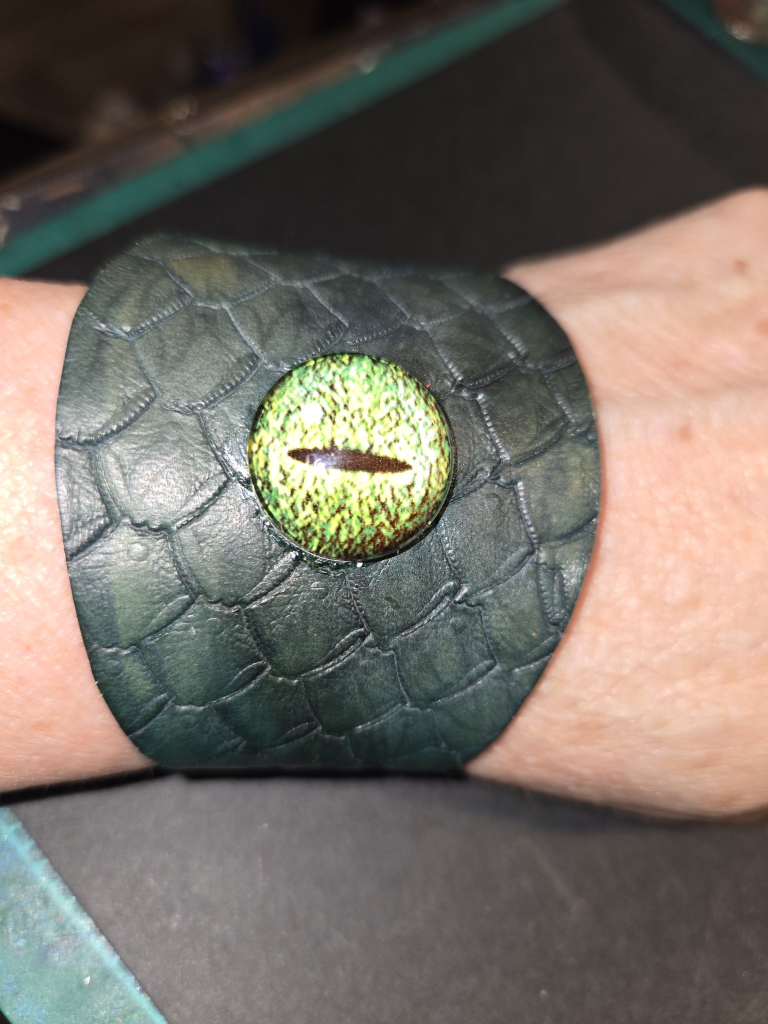 Stock 221 green dragon scale leather cuff with a vivid green dragon eye, shown on a wrist
