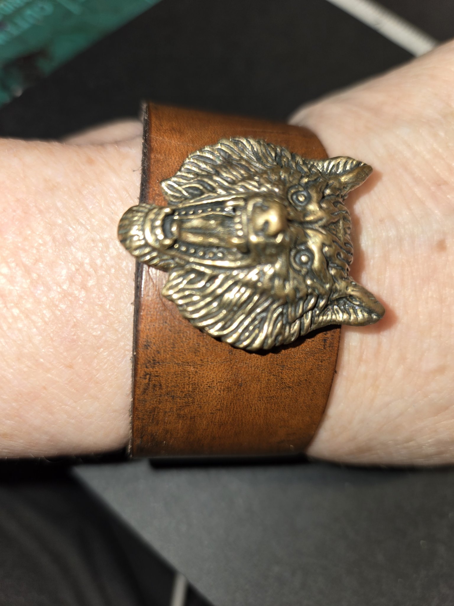 Stock 222 brown leather cuff with a bold bronze wolf head, shown on a wrist