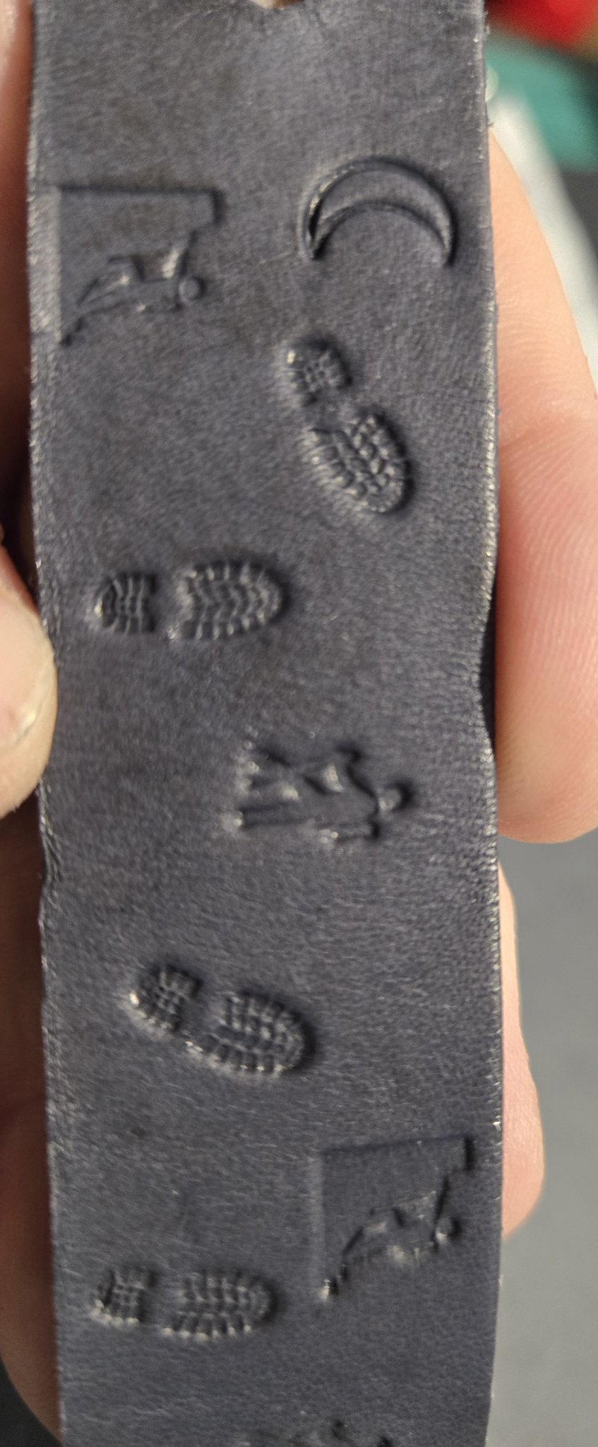 Close-up of stock 228 held in hand showing the stamped climber, crescent moon, boot prints, and hiker