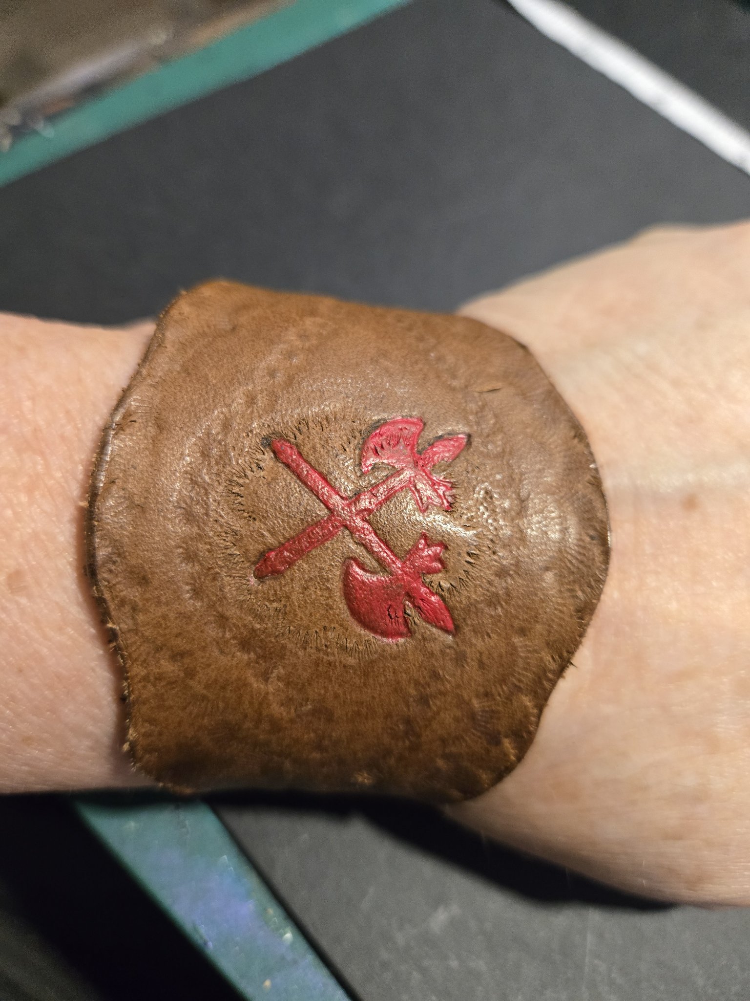 Stock 230 brown leather cuff hand-stamped and hand-painted with red crossed axes, shown on a wrist