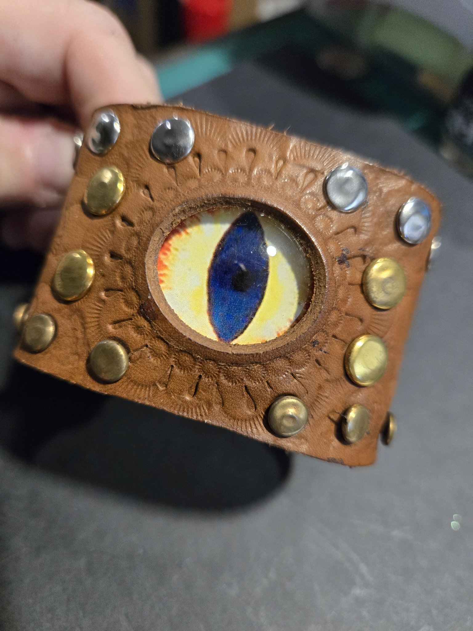 Close-up of stock 231 held in hand showing the blue and yellow dragon eye and its gold and silver tone studs